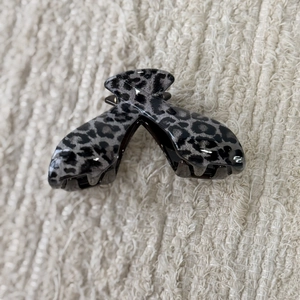 Close-up of grey leopard print hair claw clip on soft white textured fabric