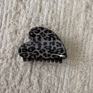 Detail view of heart-shaped leopard print hair claw clip on soft knitted background
