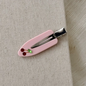 Dettaglio del fermaglio per capelli in acetato rosa con ciliegie di strass e clip in metallo