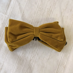 Gros plan sur la pince à cheveux noeud en velours moutarde avec texture de tissu
