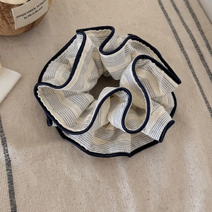 Vintage striped fabric scrunchie in beige with navy blue stitching on a linen surface
