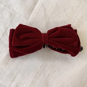 Détail de la barrette nœud en velours bordeaux montrant la texture douce et le clip banane