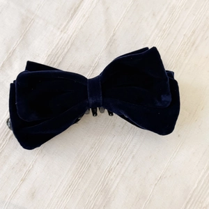 Gros plan d'une grande barrette à nœud en velours bleu marine avec des couches de tissu
