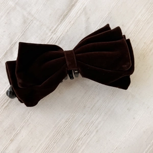 Détail du design de nœud en velours superposé sur une pince à cheveux banane marron
