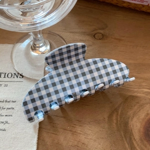 Detail view of a blue and white gingham pattern hair claw clip on a wooden table