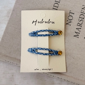 Détail macro de barrettes à carreaux bleus avec strass jaunes sur carte présentoir