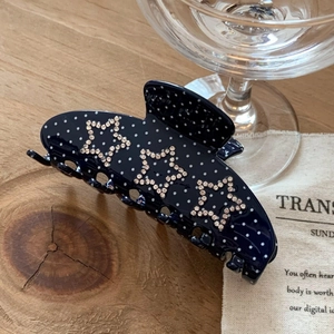 Detail of navy blue polka dot hair claw clip with sparkling rhinestone stars
