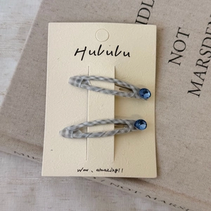 Détail de barrettes à carreaux avec strass bleus sur un décor de livre ancien