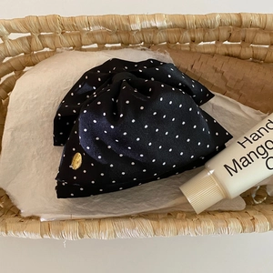 Detail of elegant black polka dot satin bow hair clip placed in a woven basket