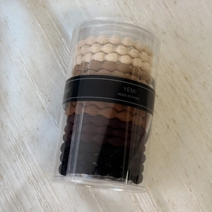 Detailed view of elastic wavy hair ties in gradient beige to coffee shades in a plastic tube