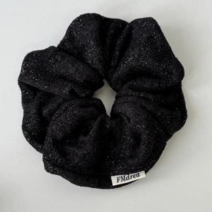 Dettaglio dell'elastico per capelli nero glitterato con fili d'argento e etichetta