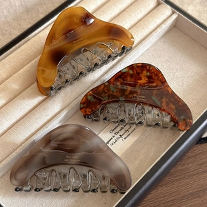 Three elegant acetate hair claws in amber, tortoiseshell, and grey tones for women