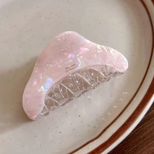 Detail of pink acetate hair claw with pearlescent marble texture on a ceramic plate