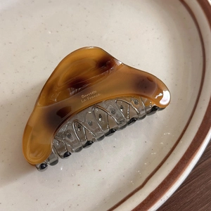 Macro shot of acetic acid hair claw clip with amber tortoise shell texture and vintage print