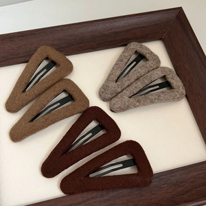 Close-up of triangle wool knit BB hair clips in warm autumn tones and metallic finish