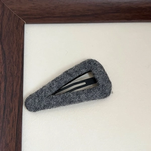 Detailed close-up of dark grey wool felt teardrop snap hair clip with warm winter texture