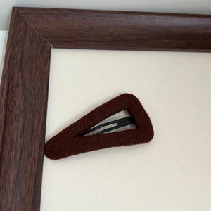 Detail of dark brown velvet triangular BB hair clip with elegant matte fabric texture
