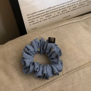 Detailansicht von blauem Haargummi mit gelben Punkten und Made in Korea Etikett
