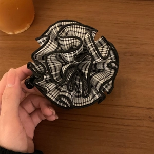 Close-up of fluffy black and white checkered scrunchie with layered fabric pleats