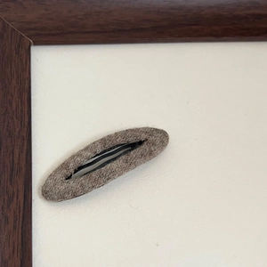 Dettaglio di un fermaglio per capelli BB ovale in feltro marrone scuro per l'autunno