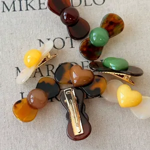 Retro mini geometric hair clips in various earth tones on a canvas background