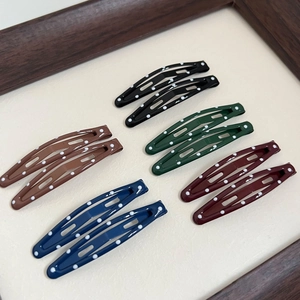 Set of 10 vintage polka dot BB hair clips in five colors on a wooden frame background