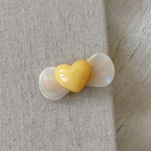 Detailed macro view of a cute resin bow hair clip with a bright yellow 3D heart center