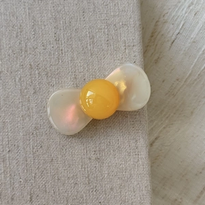 Detailed macro view of an elegant aurora ribbon hair clip with a bright yellow sphere center