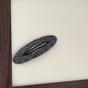 Dettaglio della trama in feltro grigio sulla clip per capelli BB ovale minimalista