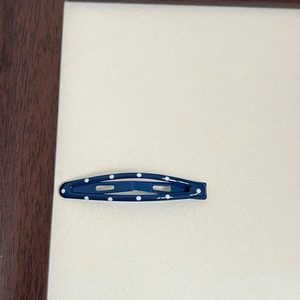 Detail of dark blue polka dot hair clip with white dots and glossy hollow design