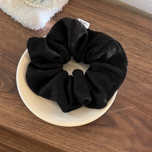 Gros plan d'un chouchou noir en maille tricotée avec étiquette sur assiette céramique