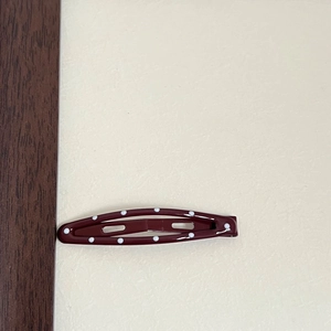 Detailed view of a dark red metal snap clip with classic white polka dot pattern