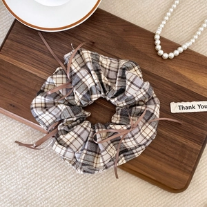 Plaid scrunchie with brown ribbons shown on a wooden background with pearl decor