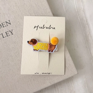 Detailed close-up of embroidered dachshund hair clip with yellow polka dot sweater on card