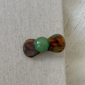 Close-up of a vintage dark green bead and tortoiseshell acetate hair clip on linen