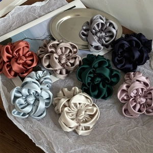 Chouchous fleurs en satin élégants de couleurs variées présentés sur un fond minimaliste