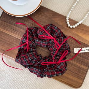 Detail of red and black tartan scrunchie with long silk ribbons on a wooden tray