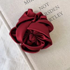 Gros plan d'un élastique à cheveux élégant en satin bordeaux avec rose en tissu