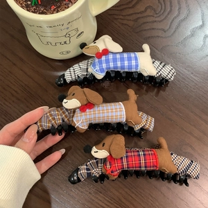 Three cute cartoon dachshund dog hair clips with checkered clothes on a dark wood background