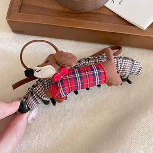 Detail of dachshund dog hair claw clip with red plaid sweater on a wooden tray