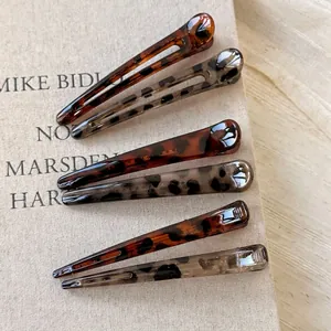 Set of 6 high-gloss leopard and tortoiseshell resin hair clips on a linen background