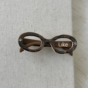 Macro shot of tortoise acetate sunglass shaped hair clip with Like text and rhinestones