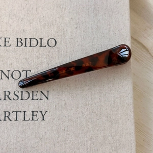 Macro shot of slim tortoiseshell hair clip with dark brown resin texture on fabric