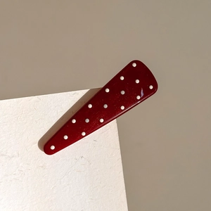 Detail of the elegant burgundy triangle hair clip with white polka dots and glossy resin finish