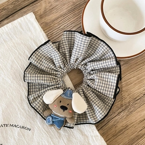 Cute cartoon puppy doll plaid fabric scrunchie with blue overalls on a wooden table