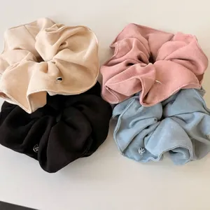 Set of four knitted scrunchies in cream, pink, black and blue with metal charm detail