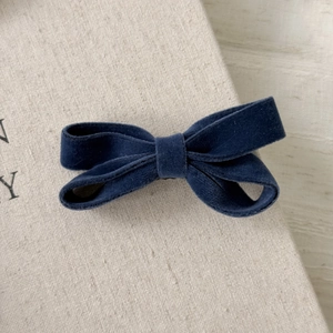 Detailed close-up of a vintage dark blue velvet bow hair clip on a minimalist book