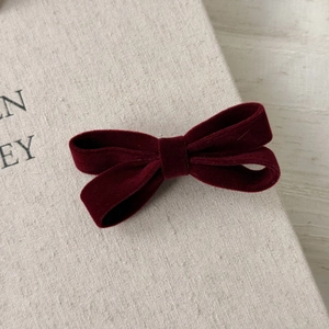 Detail of a burgundy velvet bow hair clip showing soft fabric texture and double-fold design