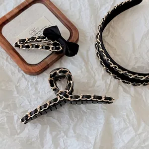 Elegant Hepburn style black leather and gold chain hair clip set on a white background