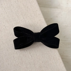 Detailed view of black velvet double-layer bow hair clip on a natural linen background